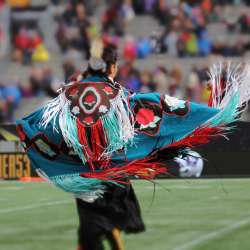 Indigenous dancer in regalia at sports event